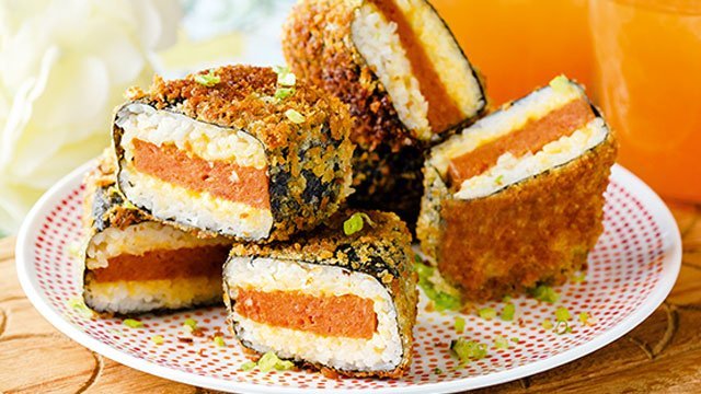 Four deep fried Spam musubis on a decorative plate.