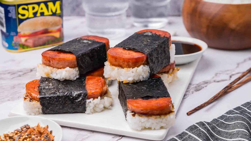 Several Spam musubis stacked on each other with a dipping sauce.